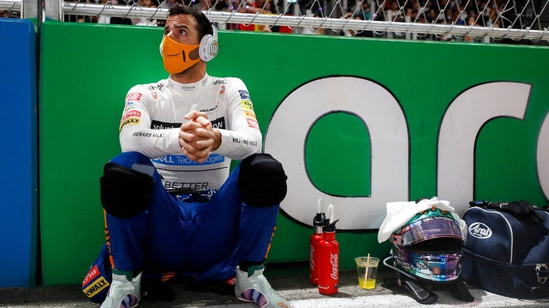 Race car driver with mask squatting on a bench