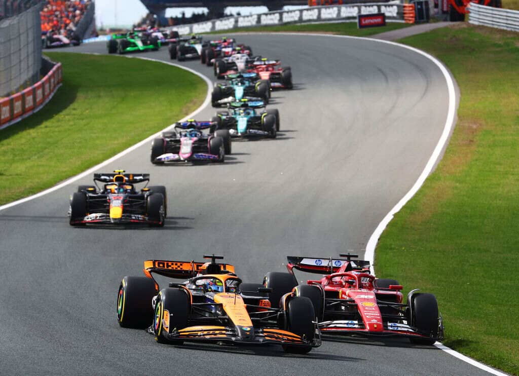 F1 cars taking a corner on a track.